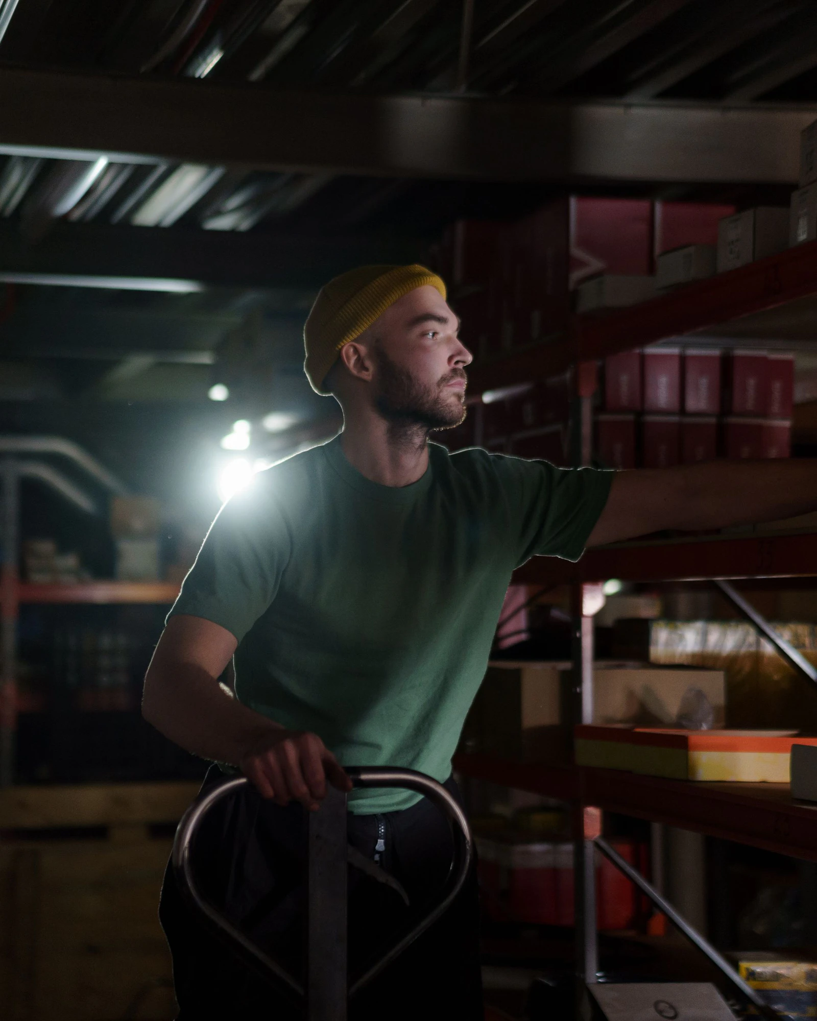 A warehouse worker pulling a pallet jack through a dim aisle